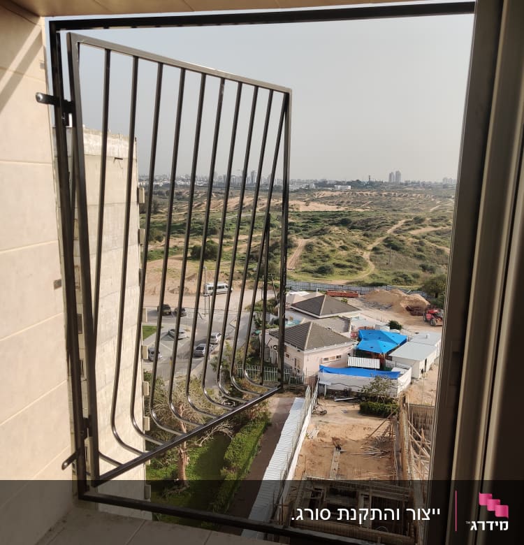 סורג מתכת פתוח בחלון עם נוף חיצוני